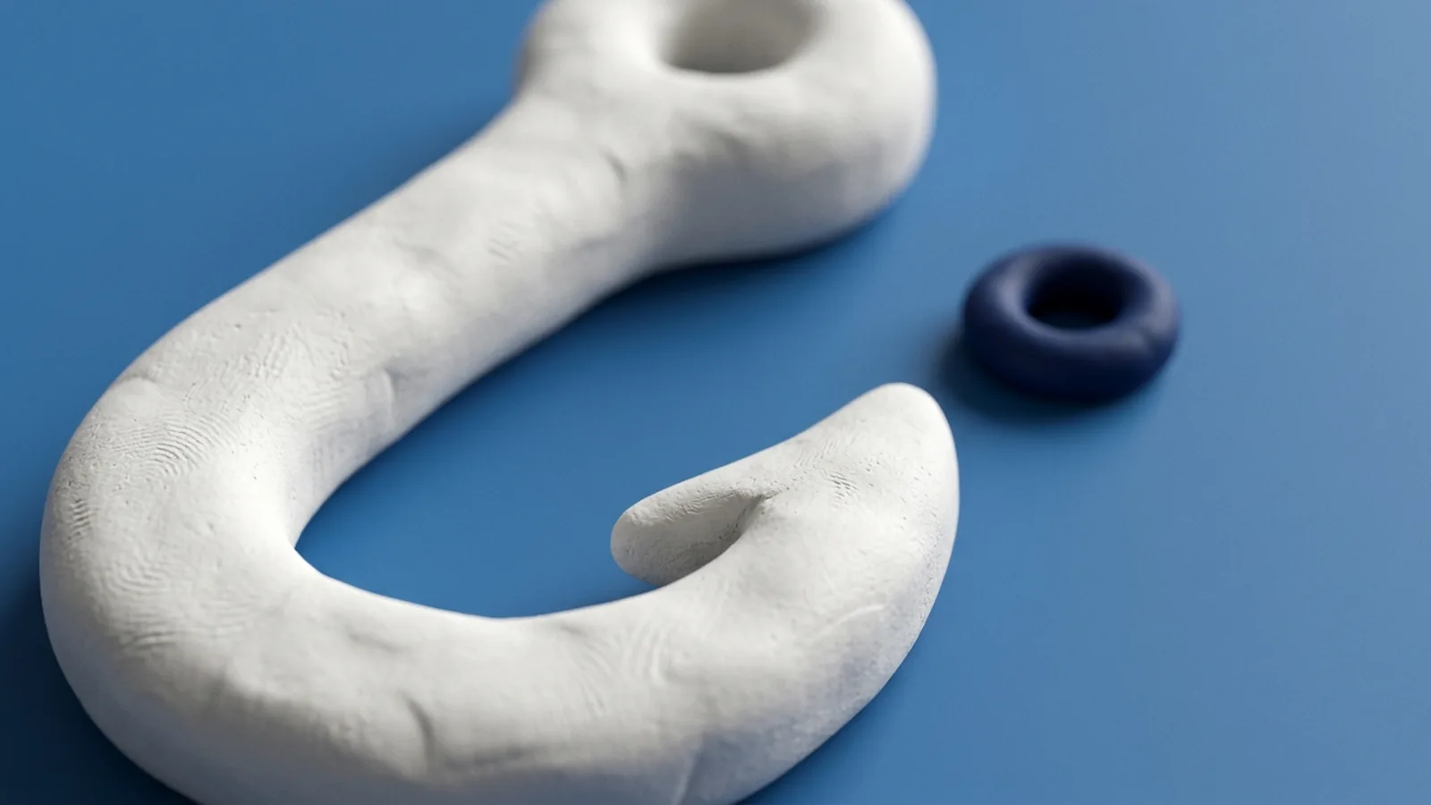 White clay illustration of a fish hook with a blank pale-blue sheet of paper hanging from it, and a small traffic cone